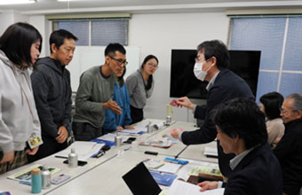 バードメイトピンバッジや風呂敷などの寄付ツールの紹介をする景山室長